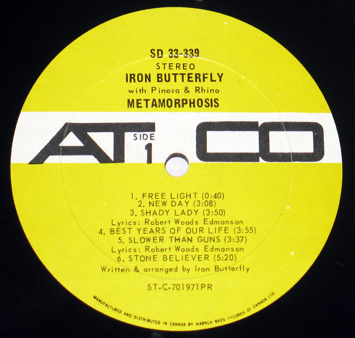 Close-up of the yellow and white ATCO Records label from Iron Butterfly's 'Metamorphosis' album, catalog number SD 33-339. The black vinyl record label features a bold ATCO logo split in two, with 'Side 1' printed underneath. The tracklist includes six songs, with credits to lyricist Robert Woods Edmonson and Iron Butterfly. The text at the bottom states it was manufactured and distributed in Canada by Warner Bros. Records.