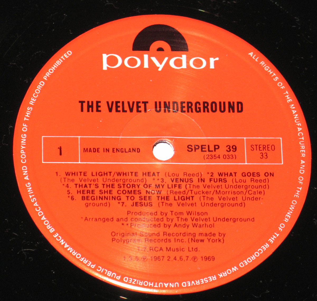 Close-up of Side One of The Velvet Underground's self-titled album on Polydor Records. The red label features the Polydor logo at the top, with bold black text displaying the band's name. The tracklist is arranged in a structured format, including 'White Light/White Heat' and 'Venus in Furs.' Production credits list Tom Wilson and Andy Warhol, with 'Made in England' and catalog number SPELP 39. The hole in the center is clean and precisely cut.