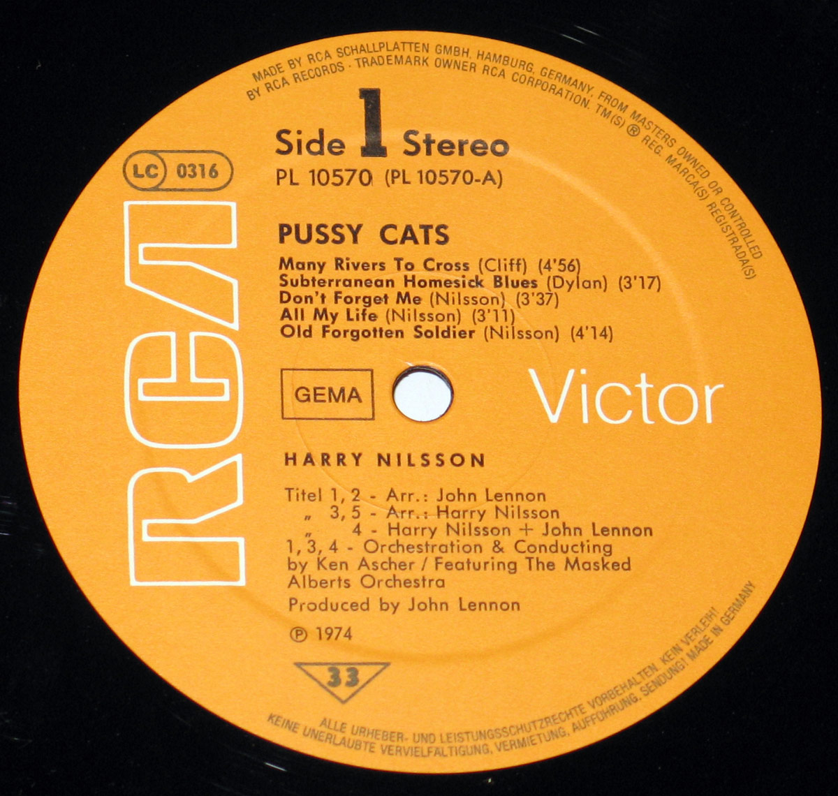 Close-up of Side One record label for 'Pussy Cats' by Harry Nilsson, produced by John Lennon. The label is bright orange with bold white 'RCA' lettering on the left side. It displays the album title 'Pussy Cats' in black capital letters, with track listings for Side 1: 'Many Rivers to Cross,' 'Subterranean Homesick Blues,' 'Don’t Forget Me,' 'All My Life,' and 'Old Forgotten Soldier.' 'Side 1 Stereo' and catalog number 'PL 10570 (PL 10570-A)' are printed at the top. Below the tracklist, credits indicate arrangement contributions from John Lennon and Harry Nilsson, as well as orchestration by Ken Ascher. The German copyright notice and 'GEMA' logo are also visible, marking it as a Deutsche Pressing.