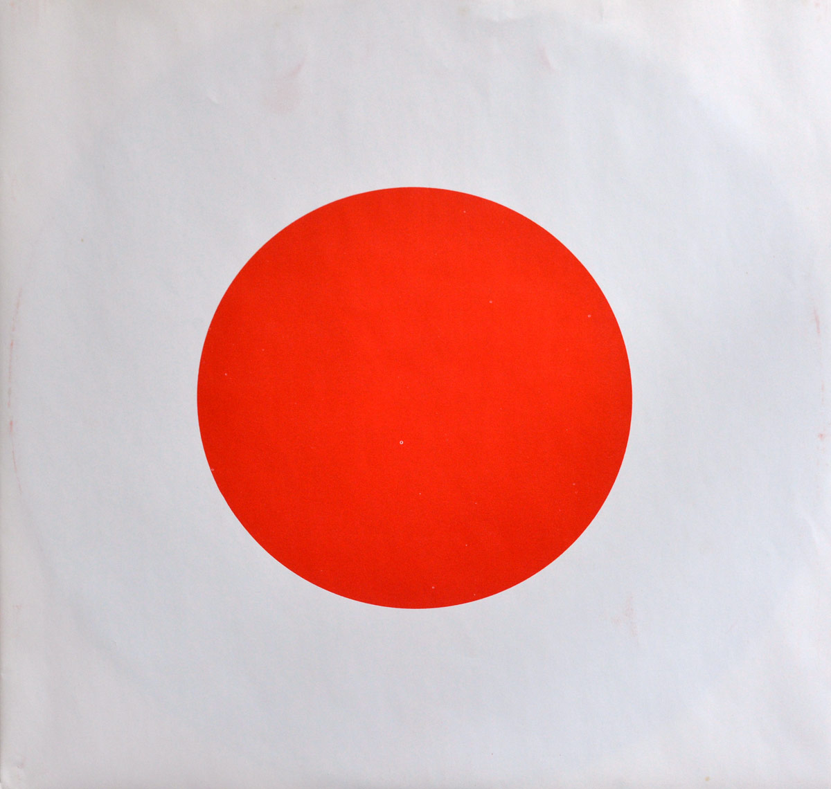 Minimalist design of the inner sleeve of John Lennon's 'Shaved Fish' album, featuring a large, bold red circle centered on a white background, resembling the Japanese flag. The design is stark and simple, reinforcing the album's aesthetic and themes.