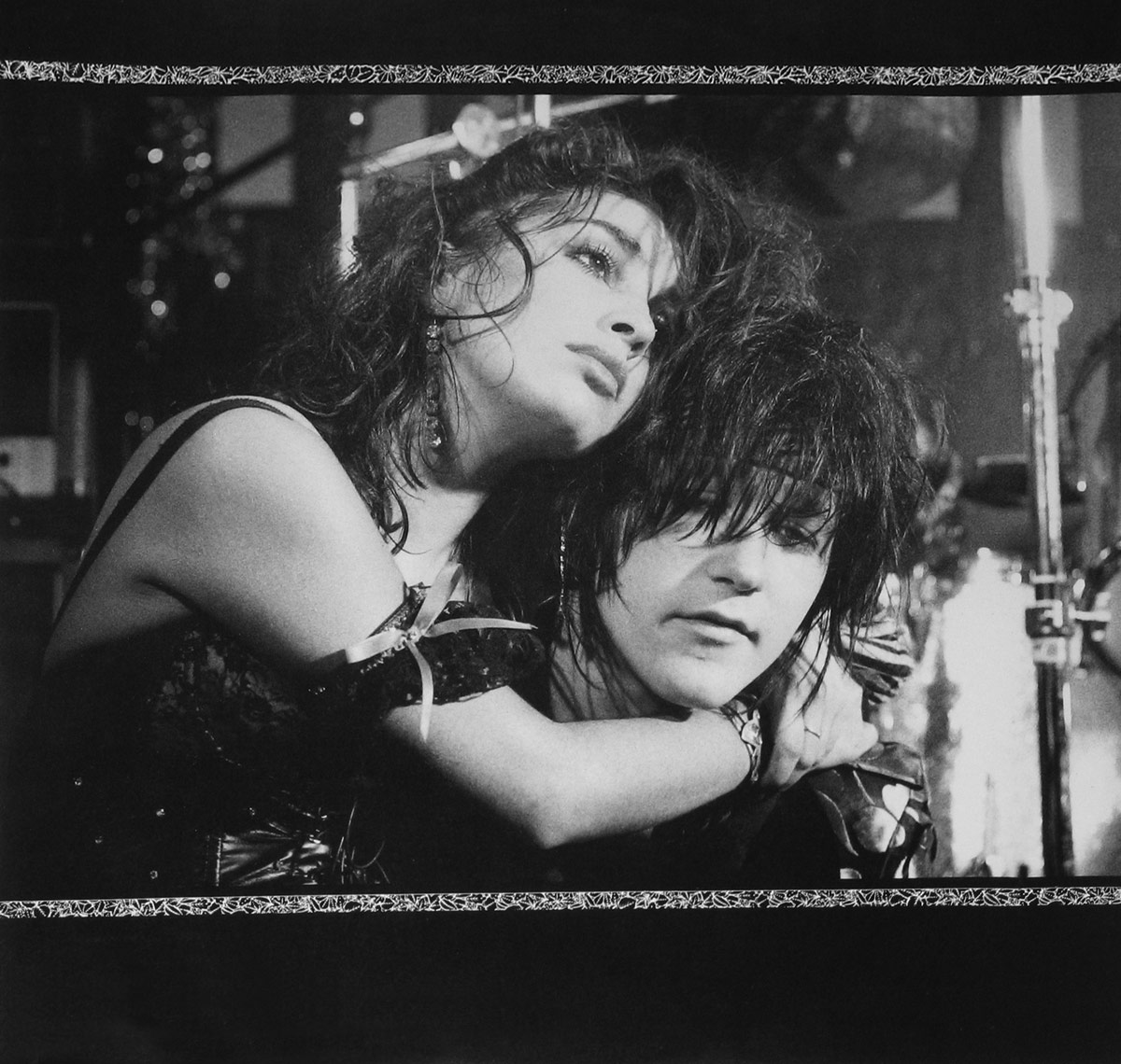 Black-and-white close-up of Cherry Bombz's Anita Chellemah and Nasty Suicide in an emotional embrace on stage, highlighting their intense glam-punk presence and raw performance energy.