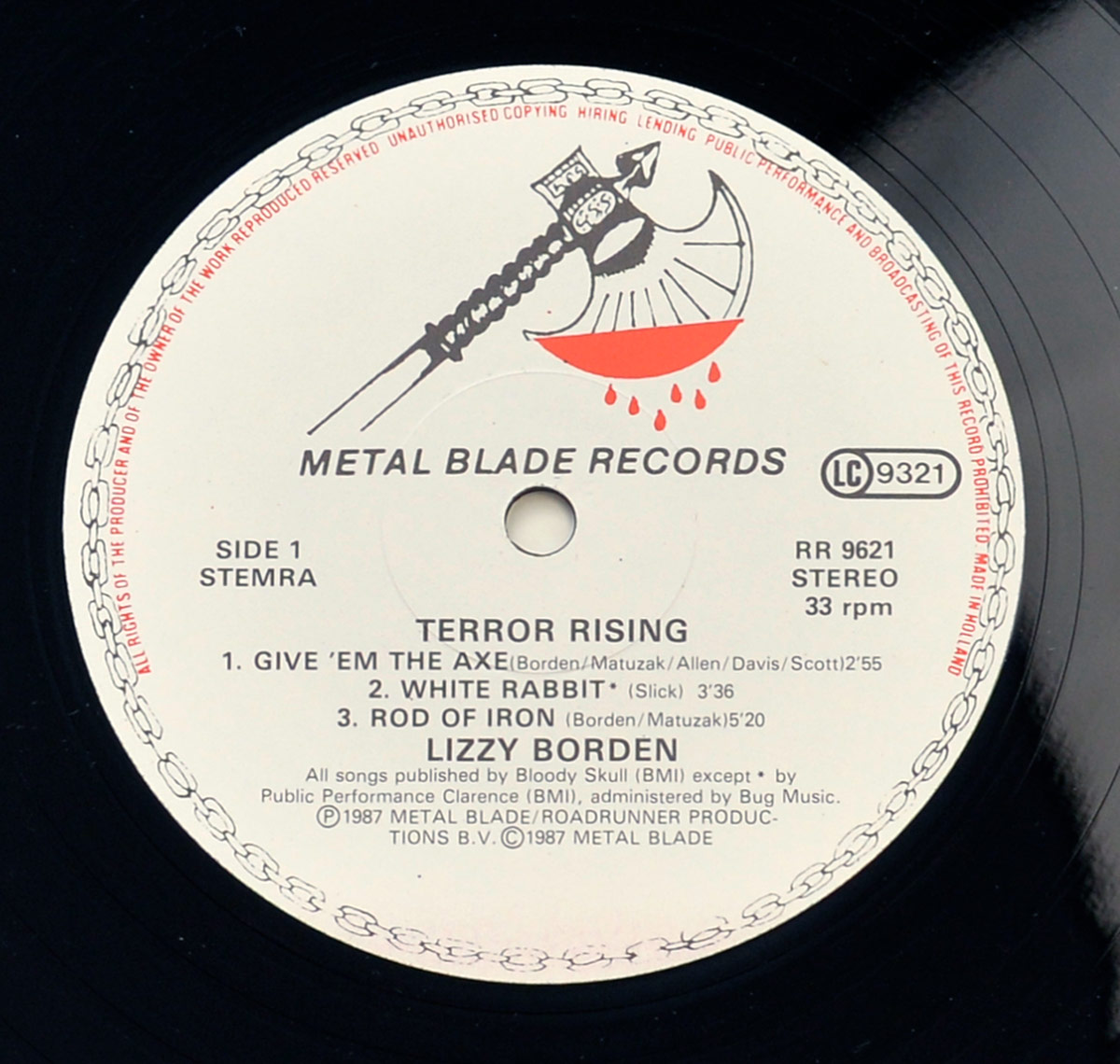 Side 1 label of Lizzy Borden's 'Terror Rising' 12-inch Vinyl EP, released by Metal Blade Records. Features the Metal Blade axe and shield logo dripping with blood, black text on a white background, and tracklist details for Side 1, including 'Give 'Em The Axe,' 'White Rabbit,' and 'Rod of Iron.' Catalog number RR 9621 is printed on the right.