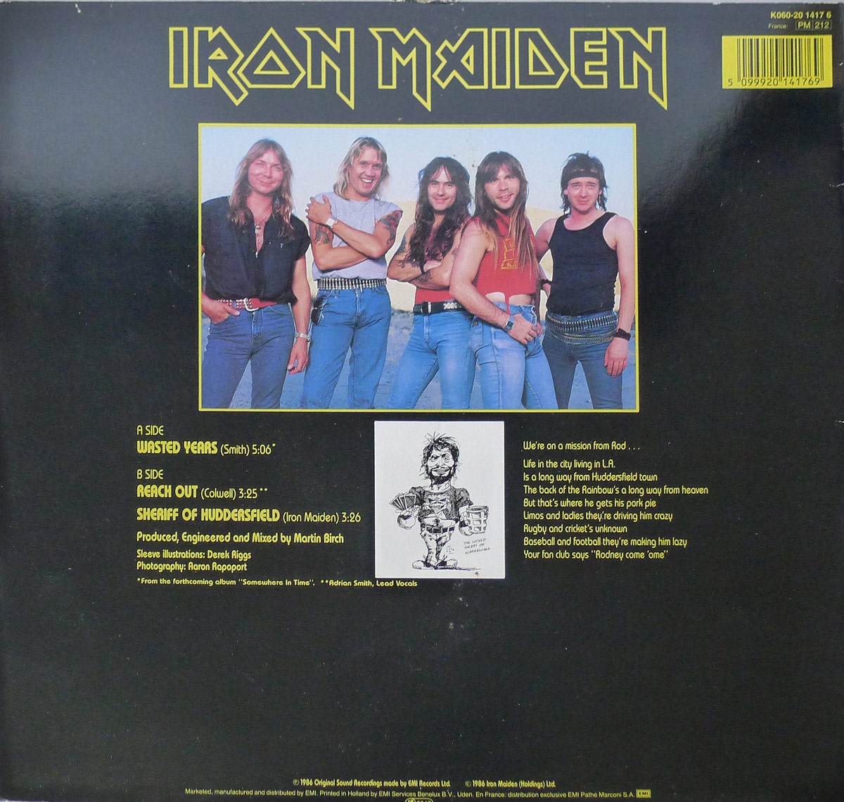 Back cover of Iron Maiden's 12-inch Maxi-Single 'Wasted Years', EMI German pressing. The layout features a band photograph framed in yellow with the five members in casual poses, wearing denim and leather against a bright sky backdrop. Track listing is printed on the left in yellow text, including 'Wasted Years,' 'Reach Out,' and 'Sheriff of Huddersfield.' Below is credit information naming Martin Birch as producer, Derek Riggs as sleeve illustrator, and Aaron Rapoport as photographer. A small black-and-white caricature illustration of the band’s manager Rod Smallwood is centered on the lower portion. To the right, humorous liner notes are printed in white text, parodying life in Los Angeles and referencing Huddersfield, limos, cricket, baseball, and football driving him lazy.