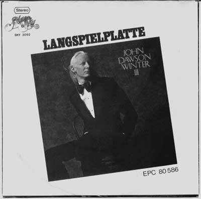 Raised on Rock's Back Cover This image features the cover for Johnny Winter’s album John Dawson Winter III, as indicated by the title on the right side of the cover. The design has a formal and elegant tone, showing Winter in a sophisticated black tuxedo with a white shirt and bow tie, a departure from his usual rock-and-roll attire. His pose is contemplative, with one hand in his pocket, giving him a poised and refined look.