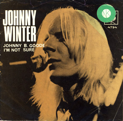 Album cover for Johnny Winter's 'Johnny B. Goode / I'm Not Sure,' featuring a monochromatic close-up of Winter singing, with bold text for the artist's name and song titles on a dark background