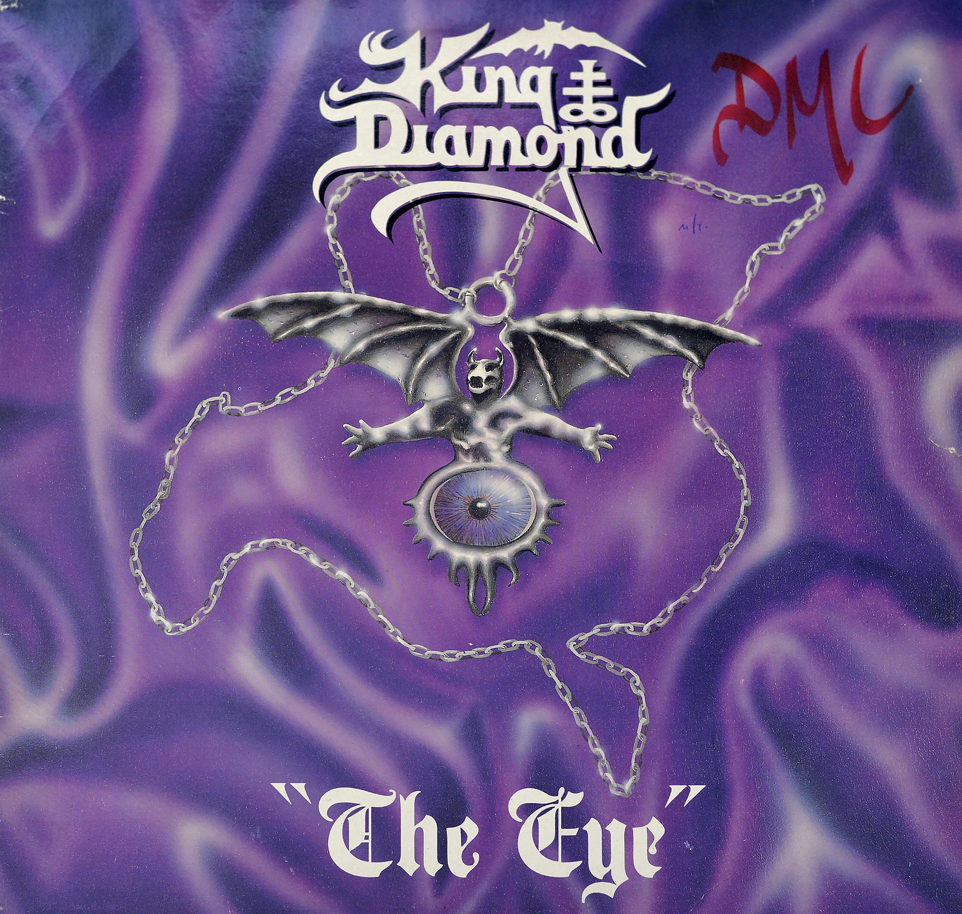 Album cover for King Diamond's The Eye featuring a purple silk background with a winged demon figure holding an open eye, suspended by a chain, and the band's logo in white gothic font at the top.