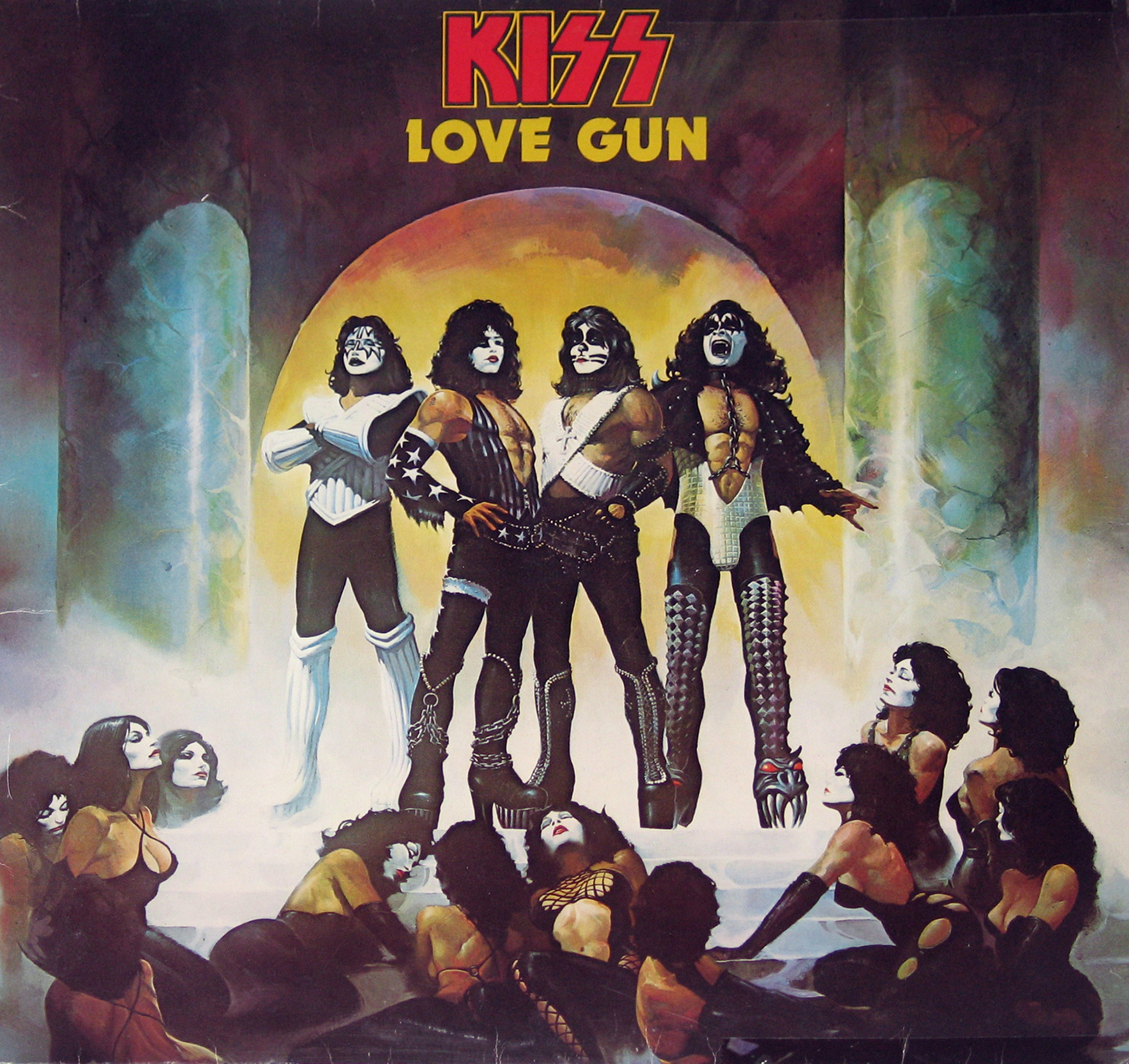 Album cover of KISS’s Love Gun, featuring the band members in their iconic makeup and costumes standing on a pedestal, surrounded by kneeling women in theatrical outfits, set against a dramatic backdrop with pillars and a glowing arch.