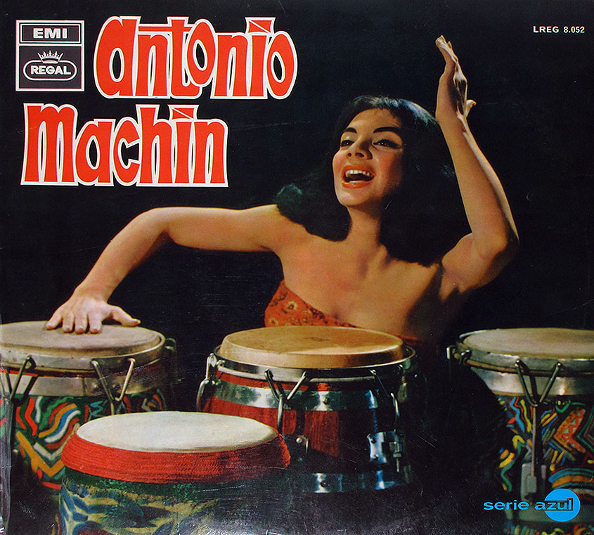 Album cover of Antonio Machín, released under EMI Regal's Serie Azul. The image features a woman with dark, voluminous hair playing five conga drums. She is dressed in a strapless, patterned top and appears mid-performance, with her right arm raised and a joyful expression on her face. The drums are vibrantly decorated, with some featuring colorful fabric patterns. The album title 'Antonio Machín' is in bold red and white stylized font at the top left, while the EMI Regal logo appears above it. The catalog number 'LREG 8.052' is in the top right corner, and 'serie azul' is written in blue lowercase letters at the bottom right. The background is black, making the subject and drums stand out vividly.