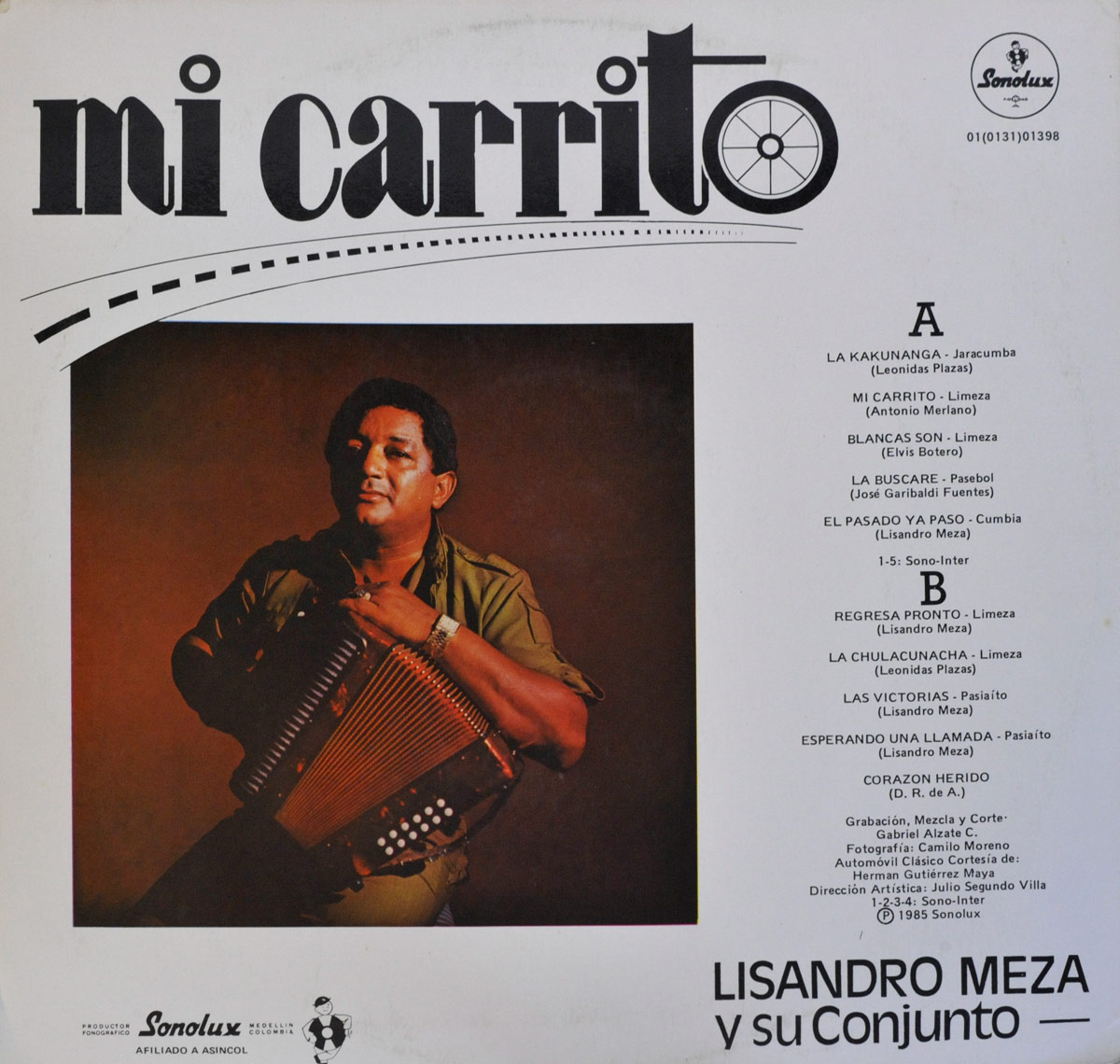 Back cover of 'Mi Carrito' by Lisandro Meza. The design features a centered photograph of Meza playing an accordion against a dark reddish-brown background. He wears an olive-green short-sleeved shirt and a gold wristwatch, looking off to the side. Above the photo, the album title 'Mi Carrito' is displayed in black stylized typography with a road and wheel illustration. To the right, the tracklist for Side A and Side B is printed in black text, listing songs with their respective composers. The Sonolux logo appears at the top right corner. At the bottom, production credits, including recording, mixing, photography, and artistic direction, are detailed. The Sonolux logo and a small emblem of an affiliated organization are also present. The overall layout is clean with a white background, black typography, and a structured composition.