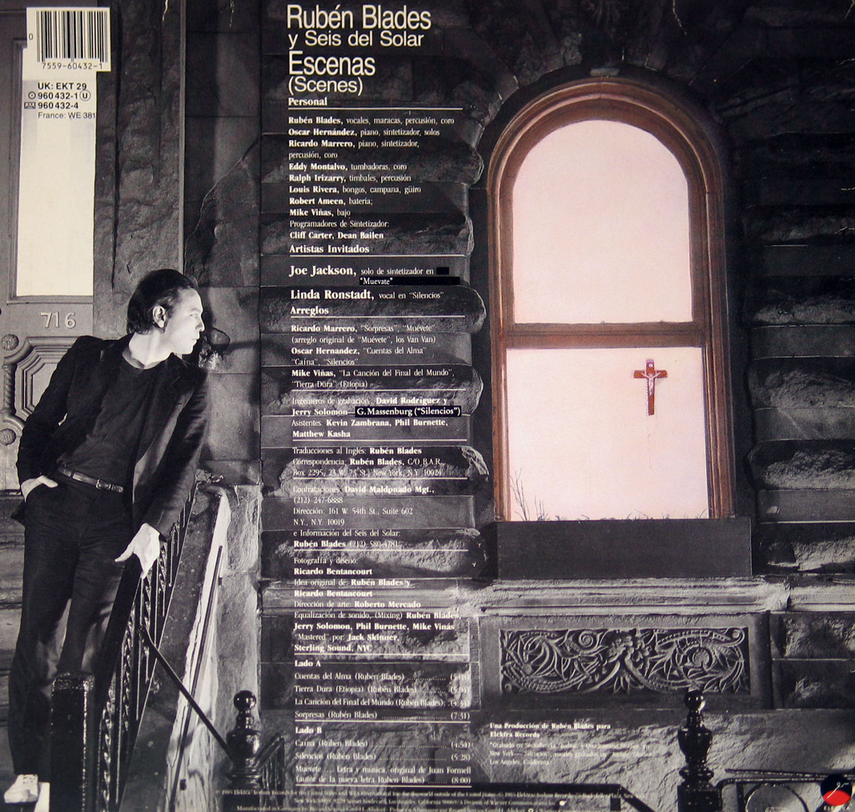Back cover of Rubén Blades' album 'Escenas' featuring a black and white photograph of a man leaning on a stair railing outside a brownstone building. A window with a crucifix hangs on a pastel-colored interior wall. The tracklist, credits, and guest artists including Linda Ronstadt and Joe Jackson are printed in white text over the image.