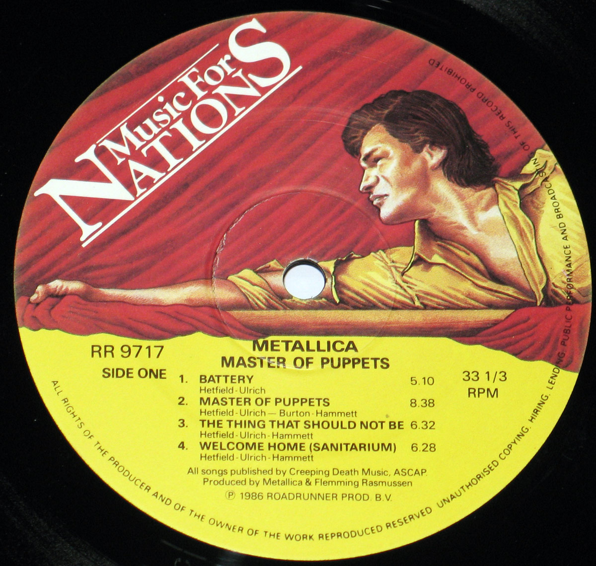 Side One record label of Metallica's 'Master of Puppets' album from Music for Nations. The label features a dramatic illustration of a muscular man in a yellow shirt gripping a bar, set against red drapery. The lower half is yellow, displaying track listings including 'Battery,' 'Master of Puppets,' and 'Welcome Home (Sanitarium),' with black text and the Roadrunner Records catalog number RR 9717.