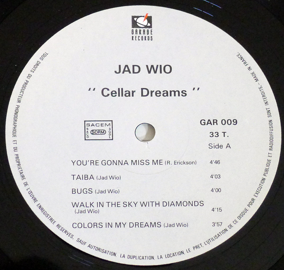 Close-up of Side A label of JAD WIO's 1986 LP 'Cellar Dreams', showing Garage Records logo, tracklist with durations, SACEM rights, catalog number GAR 009, 33 T