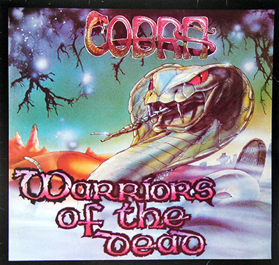 Front cover of Cobra's 'Warriors of the Dead' album. Features a large menacing cobra with cracked, stone-like scales, glowing red eyes, and long fangs, with metal chains in its mouth. The background depicts a dark graveyard with tombstones, a misty eerie landscape, and a twisted barren tree. The album title appears in a dripping blood-red font.