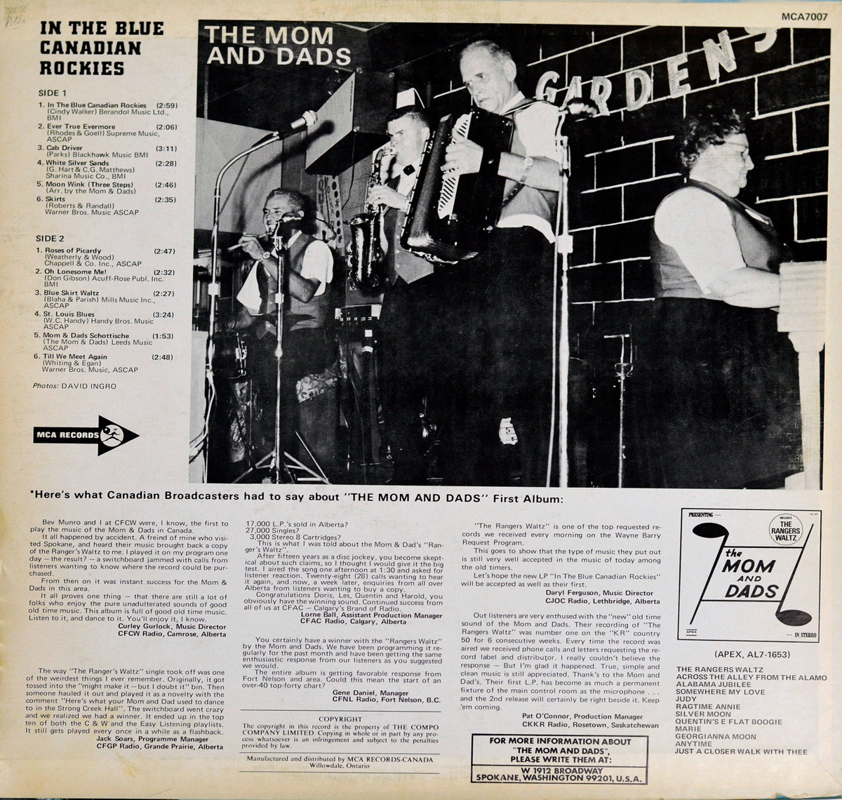 Back cover of THE MOM AND DADS - In The Blue Canadian Rockies 12-inch vinyl LP album. Features a black-and-white photo of the band performing live on stage, with accordion, drums, and keyboard. Left column shows track listings, credits, and liner notes, while the bottom section includes Canadian broadcaster reviews and MCA Records info.