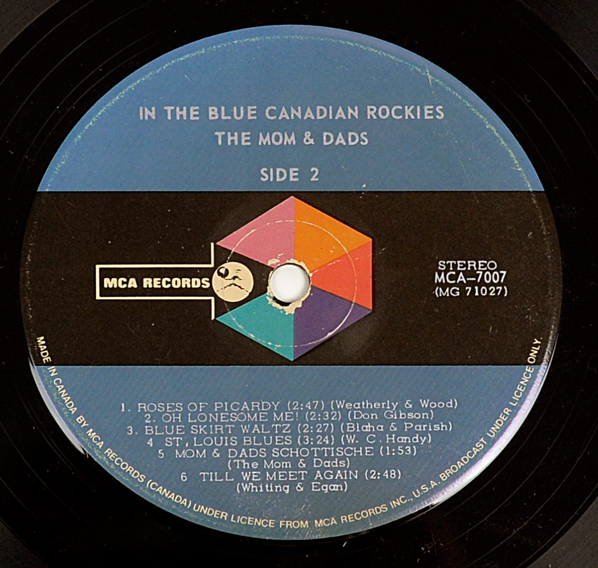 Side 2 of the vinyl LP THE MOM AND DADS - In The Blue Canadian Rockies. The MCA Records label features a bold prism logo on black background, with a blue band at the top showing title, artist, and side info. White text lists six songs including Roses of Picardy, Oh Lonesome Me, and Mom & Dads Schottische with full songwriter credits.