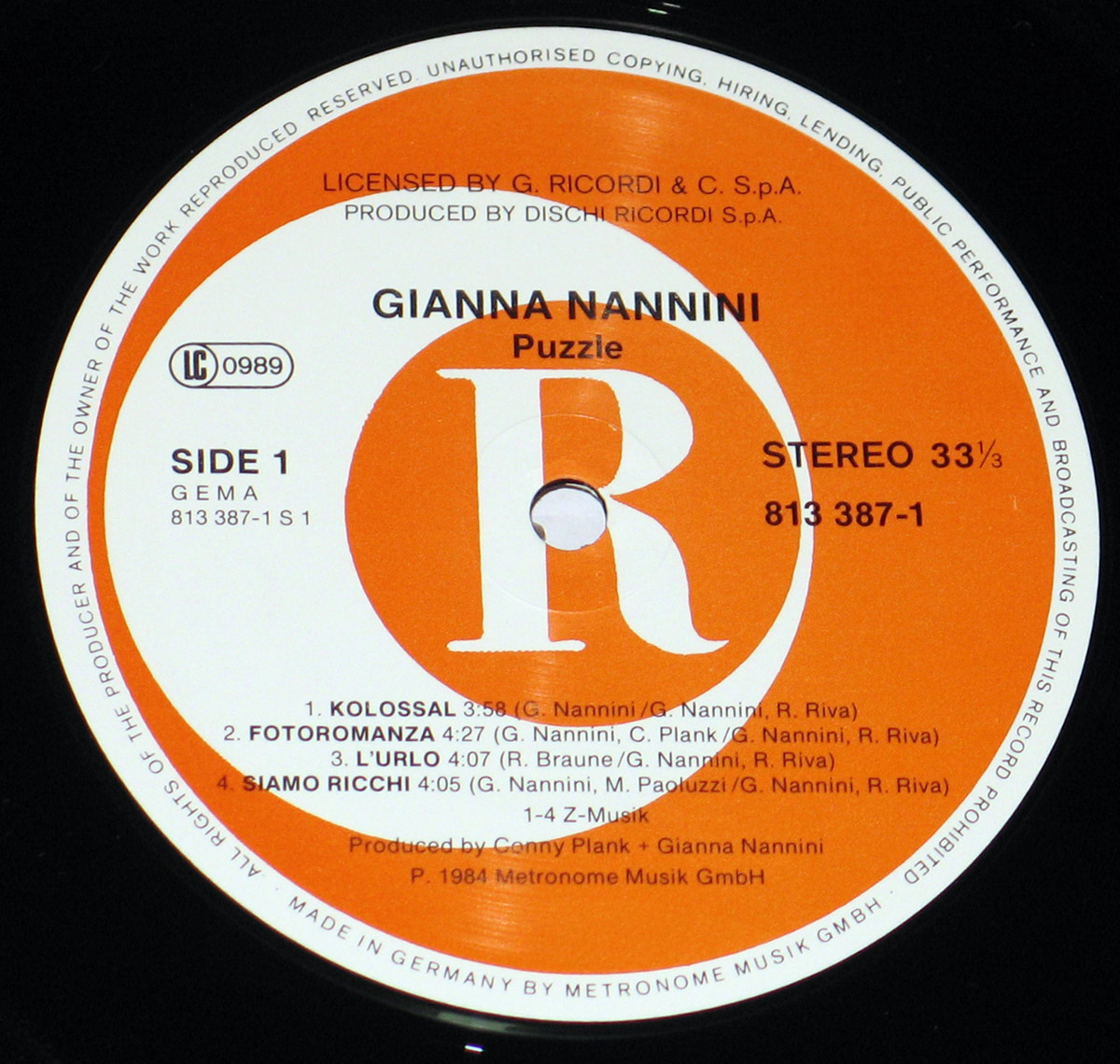 Close-up of Side One vinyl record label for the album Puzzle, showing an orange and white Metronome Musik label with large central R logo, clear track listing, catalog number 813 387-1, stereo 33 1/3 RPM marking, and German manufacturing credits printed around the rim.