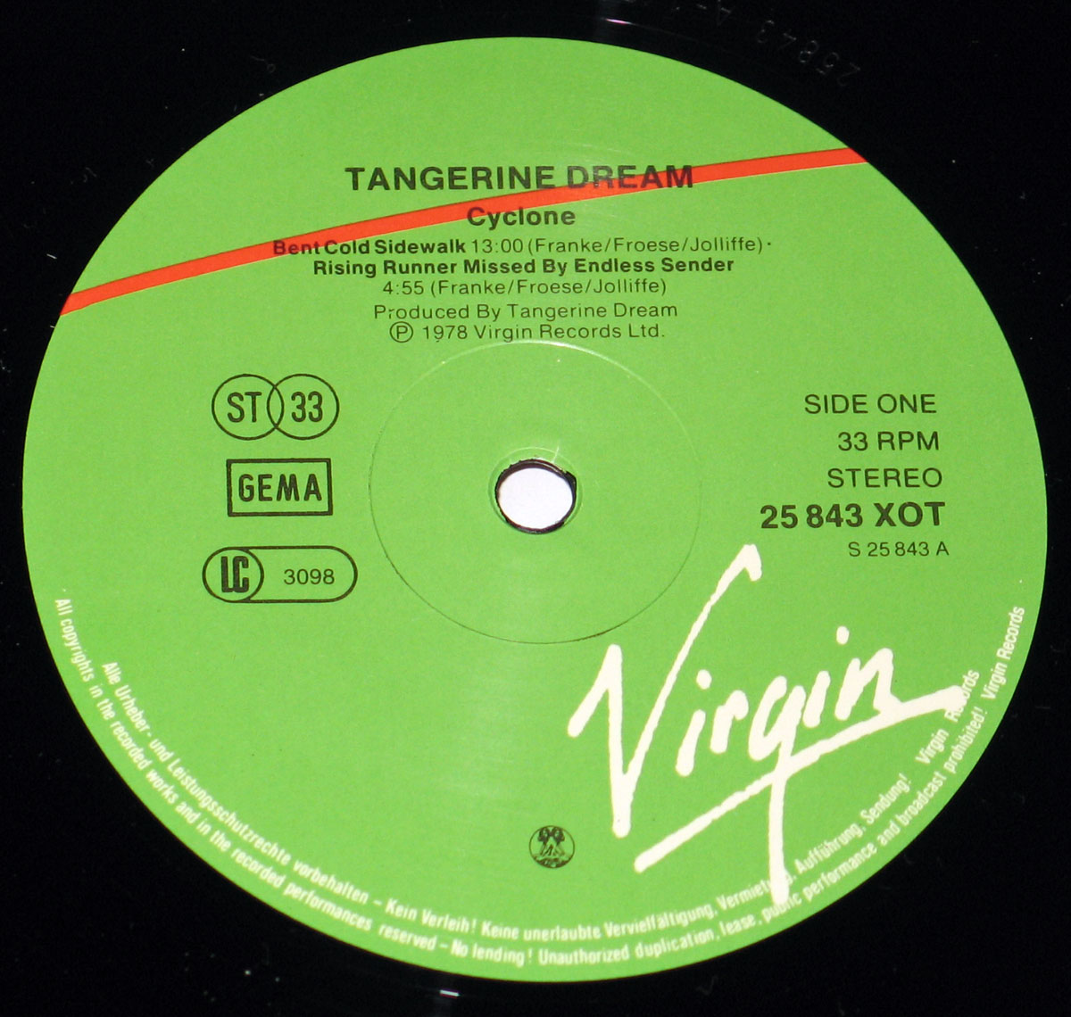 Close-up of the Side One record label from Tangerine Dream's 1978 album Cyclone, released on Virgin Records in Germany. The label is a vibrant green background with bold black and white typography. Across the top, 'Tangerine Dream' is printed in uppercase, followed by the album title 'Cyclone' beneath. Track listings for Side One are included: 'Bent Cold Sidewalk' (13:00) and 'Rising Runner Missed By Endless Sender' (4:55), with writing credits to Franke, Froese, and Jolliffe. Production is credited to Tangerine Dream. On the right side, the catalog number 25 843 XOT and Side One designation appear, alongside 33 RPM and Stereo format details. A large white handwritten-style Virgin logo dominates the lower portion. To the left, symbols for ST 33, GEMA, and LC 3098 are visible, along with copyright information circling the label’s edge. The central spindle hole is surrounded by the standard ring mark from the pressing plant.