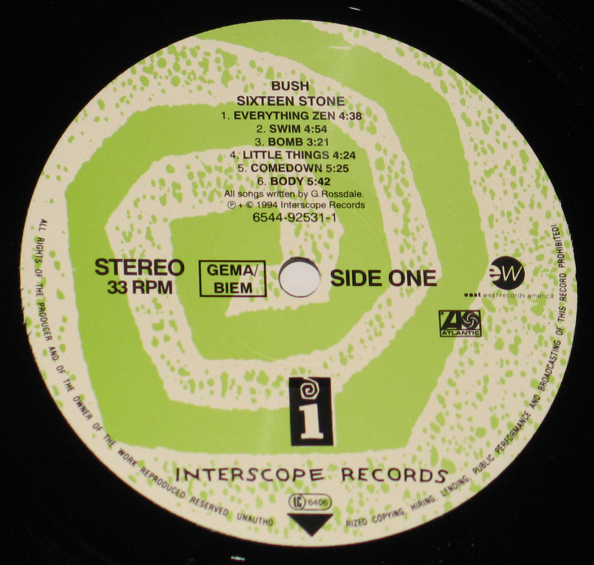 Close-up of Side One record label from BUSH - Sixteen Stone vinyl LP. The circular label has a green and white spiral pattern with a speckled texture. The album title, tracklist, and record company logos are printed in black, with 'Interscope Records' prominently displayed at the bottom.