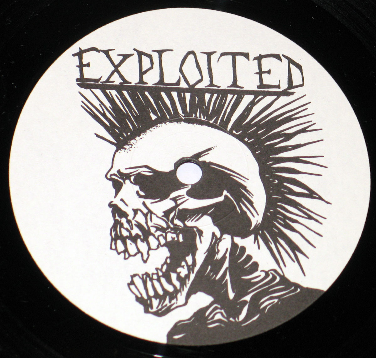 Record label artwork for The Exploited’s album Let’s Start a War… featuring a black and white illustration of a skeletal head with a mohawk and distressed text reading “Exploited” above it, designed in a raw punk style.