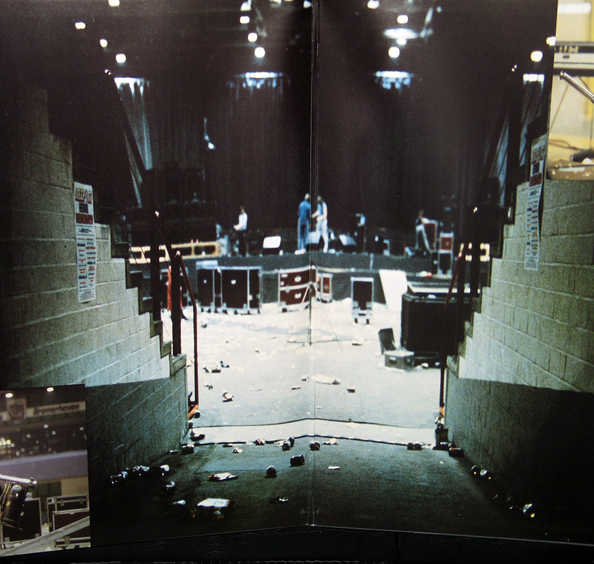 Interior gatefold photo from BAP's 'Bess demnähx' album showing a post-concert view from backstage toward the stage, with scattered trash, flight cases, and crew members breaking down equipment under overhead lights.