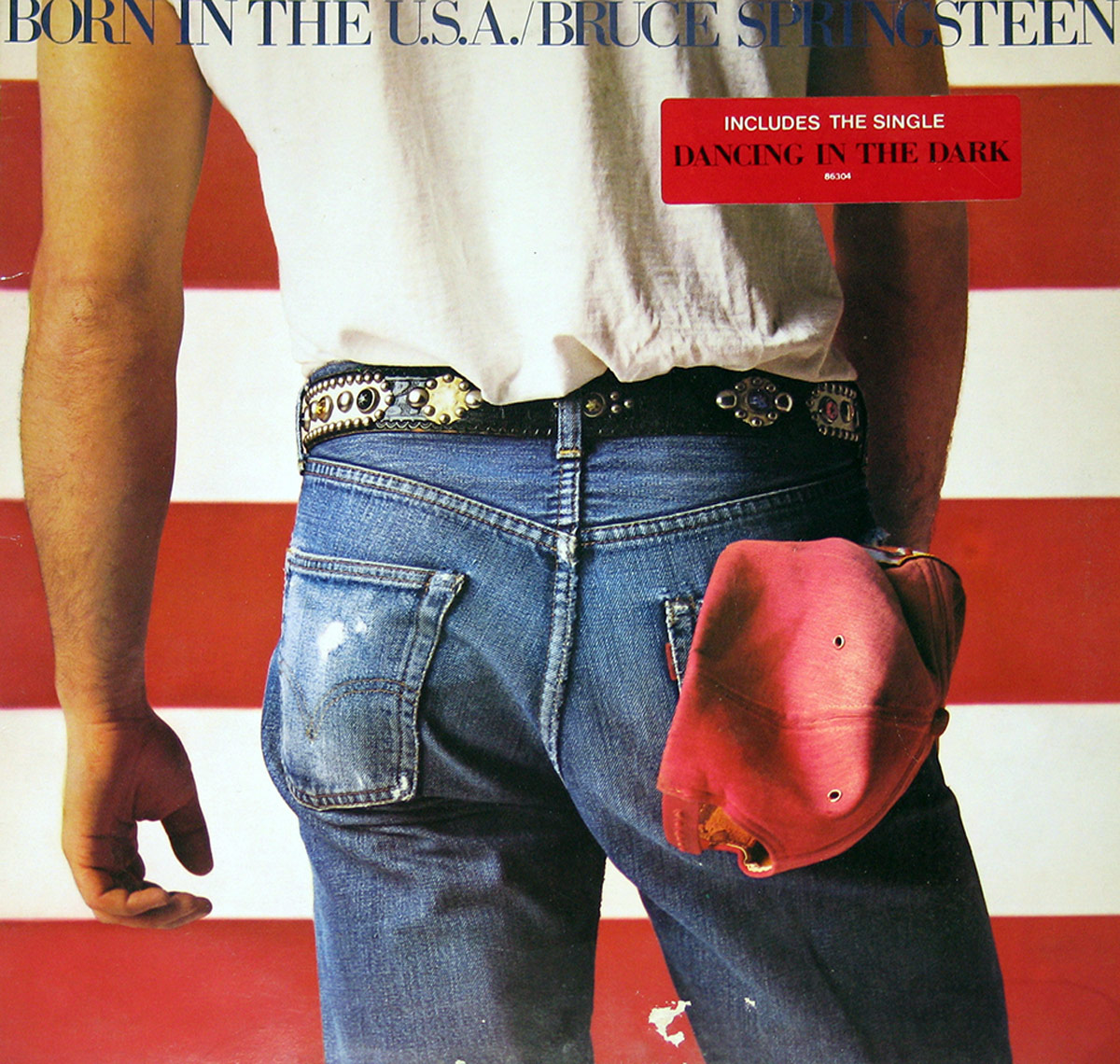 Album cover of Born in the U.S.A. by Bruce Springsteen, featuring a close-up of Springsteen's back wearing faded blue jeans with a red baseball cap in the pocket, standing in front of an American flag backdrop.