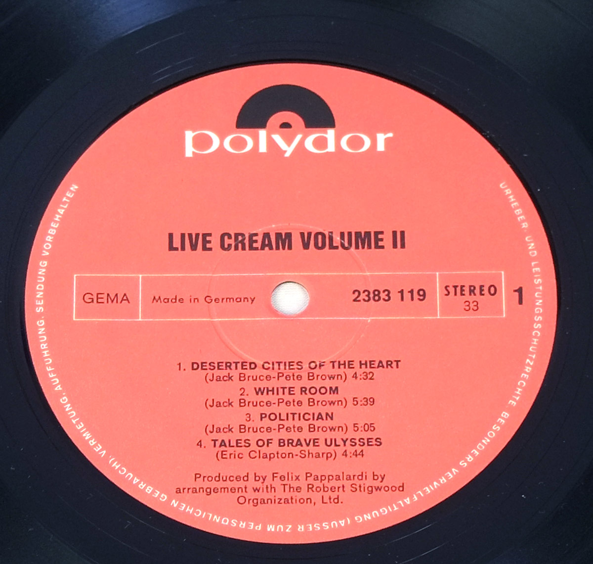 Vinyl record label of 'Live Cream Volume II' by Cream, released by Polydor. The label is red with black text and features the Polydor logo at the top. The album title, 'Live Cream Volume II,' is printed in bold uppercase letters, followed by track listings for Side One, including 'Deserted Cities of the Heart,' 'White Room,' 'Politician,' and 'Tales of Brave Ulysses.' Additional details such as the catalog number (2383 119), stereo format, and production credits for Felix Pappalardi are also present. The label indicates that the record was made in Germany and includes copyright protection text around the edge.