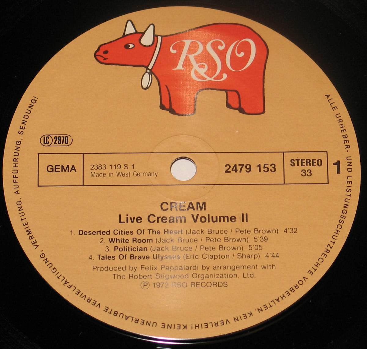 Close-up of the record label for 'Live Cream Volume II' by CREAM, released in 1972 on RSO Records. The label features a distinctive light brown background with the iconic red RSO cow logo at the top. The catalog number '2479 153' is printed on the right side, along with the stereo format and speed '33 RPM'. The track listing for Side One is displayed, including 'Deserted Cities of the Heart', 'White Room', 'Politician', and 'Tales of Brave Ulysses'. Additional text at the bottom credits producer Felix Pappalardi and the Robert Stigwood Organization. The record was manufactured in West Germany.