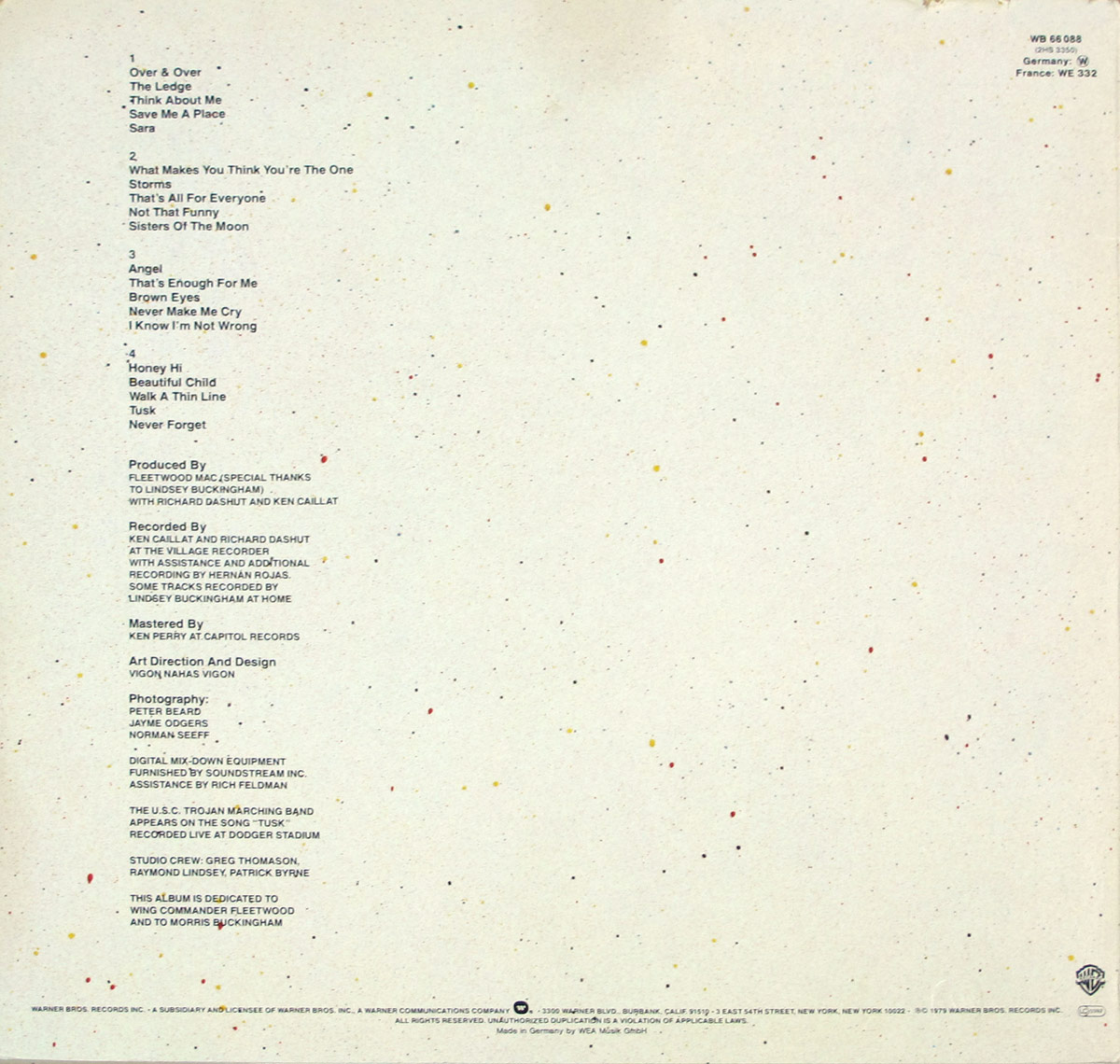 The back cover of Fleetwood Mac's 'Tusk' album maintains the minimalist aesthetic with a beige background speckled with tiny red, black, and yellow dots. The tracklist is arranged in four numbered sections, corresponding to the four sides of the double LP. The bottom portion includes production credits, design acknowledgments, and copyright details in a small, simple black font.