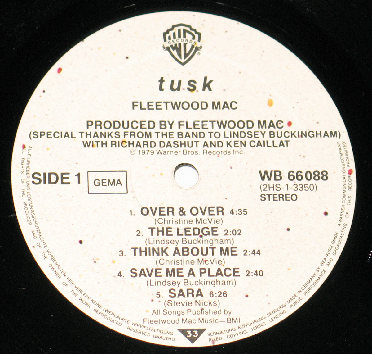 Close-up of Fleetwood Mac's Tusk Side 1 record label, featuring a white background with black text, Warner Bros. Records logo at the top, tracklist including 'Over & Over' and 'Sara,' and production credits.