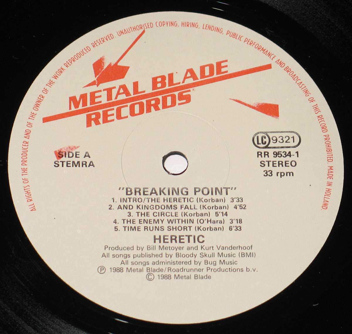 Close-up of HERETIC Breaking Point vinyl record label. The Metal Blade Records logo is prominently displayed in red at the top. The label, printed on an off-white background, includes the album title, tracklist for Side A, and production credits. The record is identified as RR 9534-1, Stereo, 33 RPM, and made in Holland. The text curves around the center hole of the black vinyl disc.