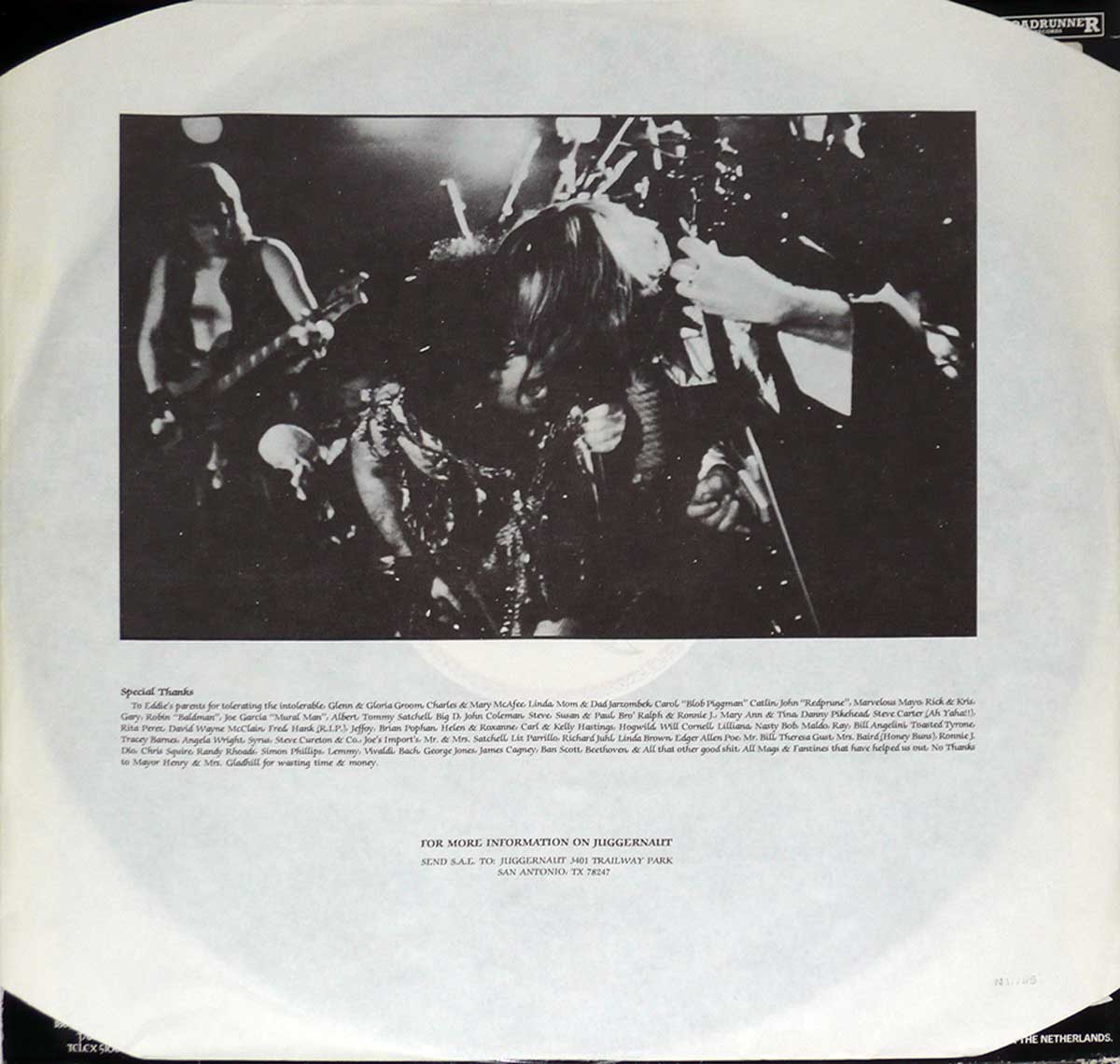 The custom inner sleeve of Juggernaut's 'Baptism Under Fire' features a high-contrast black and white live concert photograph of the band. The vocalist is seen hunched over, gripping the microphone with intensity, while the guitarist's hand reaches in from the right, strumming his instrument. The blurred background showcases another band member and stage lights. Below the image, special thanks and credits are printed, followed by a mailing address for fans seeking more information about Juggernaut.