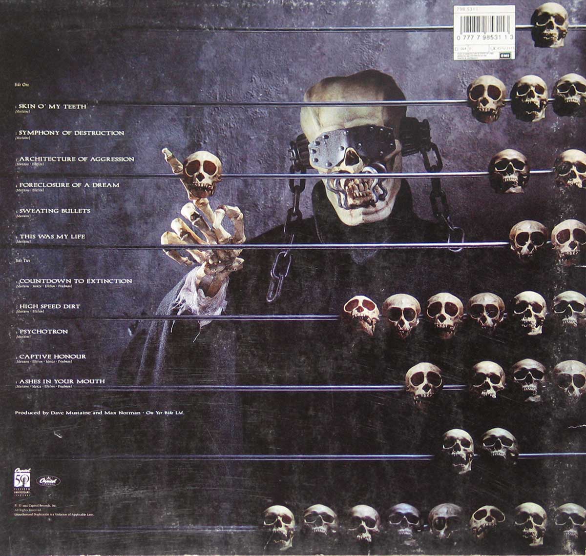 Back cover of Megadeth Countdown to Extinction LP features Vic Rattlehead shackled in a dark cell, surrounded by skulls on metal rods representing a musical staff, with track titles aligned along the bars.