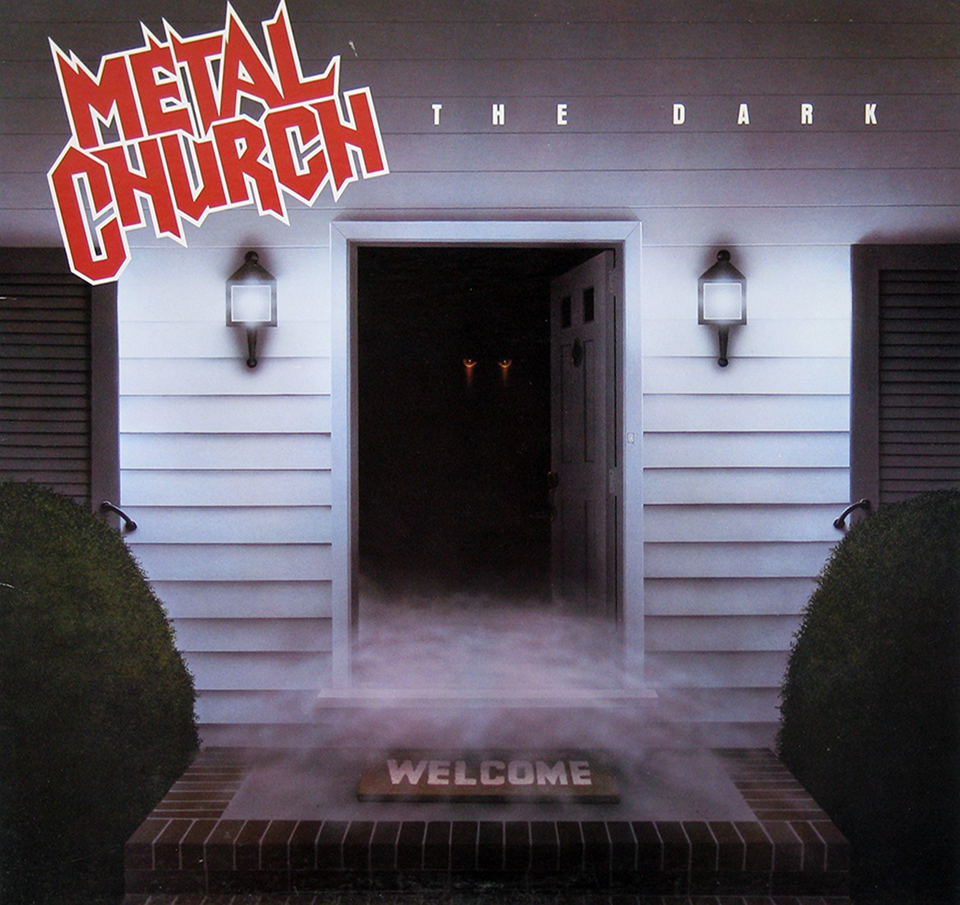 Album cover for Metal Church’s The Dark, featuring an ominous open doorway of a suburban house at night, with glowing eyes peering from the shadows, mist rolling across the brick steps, and a doormat that says WELCOME.