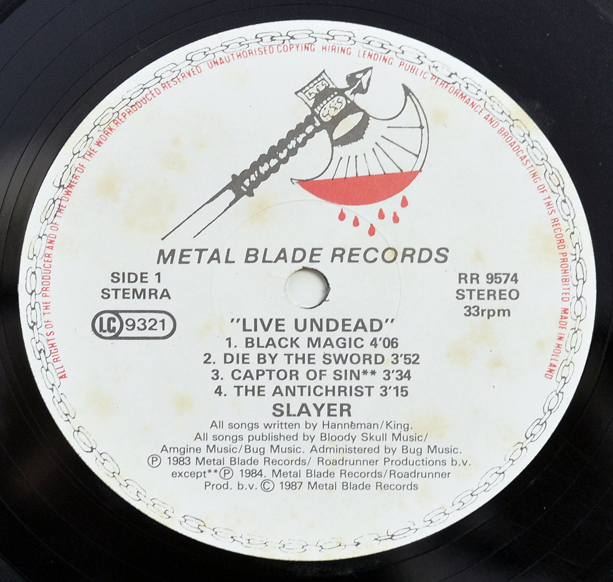 Close-up of Slayer's 'Live Undead' vinyl record label featuring the rare Metal Blade Records blood-dripping axe logo, tracklist, and catalog details for Side 1.