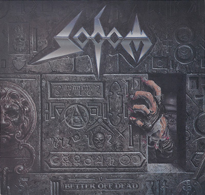 Album cover for Sodom’s Better Off Dead featuring a dark stone wall with engraved symbols, a skeletal hand reaching out from an opening, and a single eye peering from the shadows