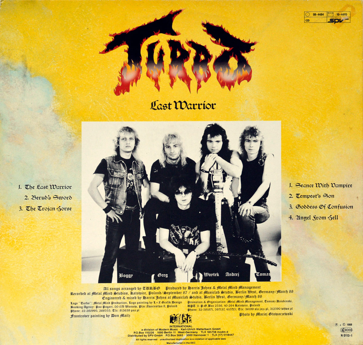 Back cover of TURBO's Last Warrior album featuring the band members' photo, track listing, credits, and production info on a yellow backdrop
