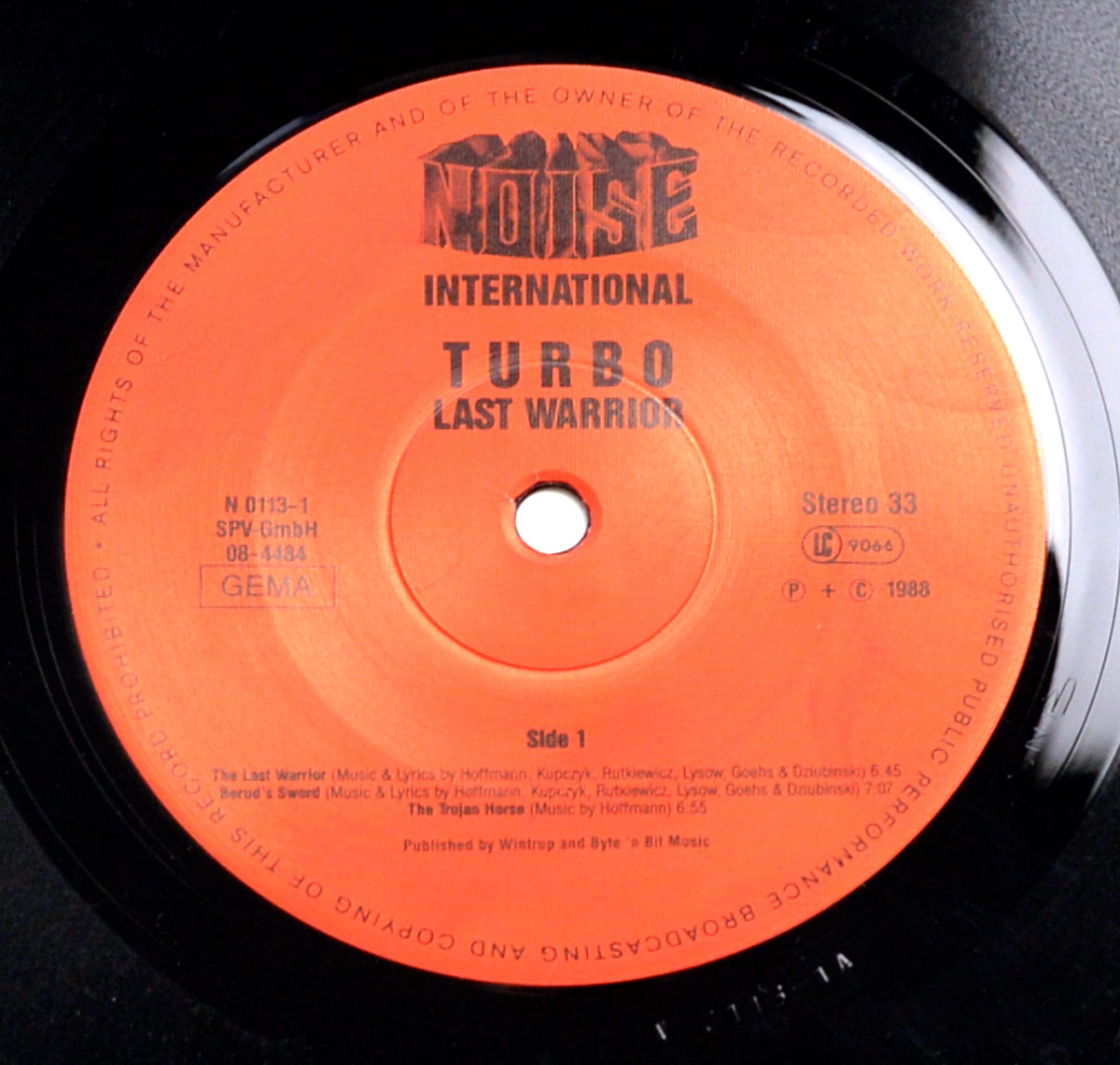 Side One record label of TURBO's Last Warrior LP on Noise International, catalog number N 0113-1, showing track titles and credits in black on orange label