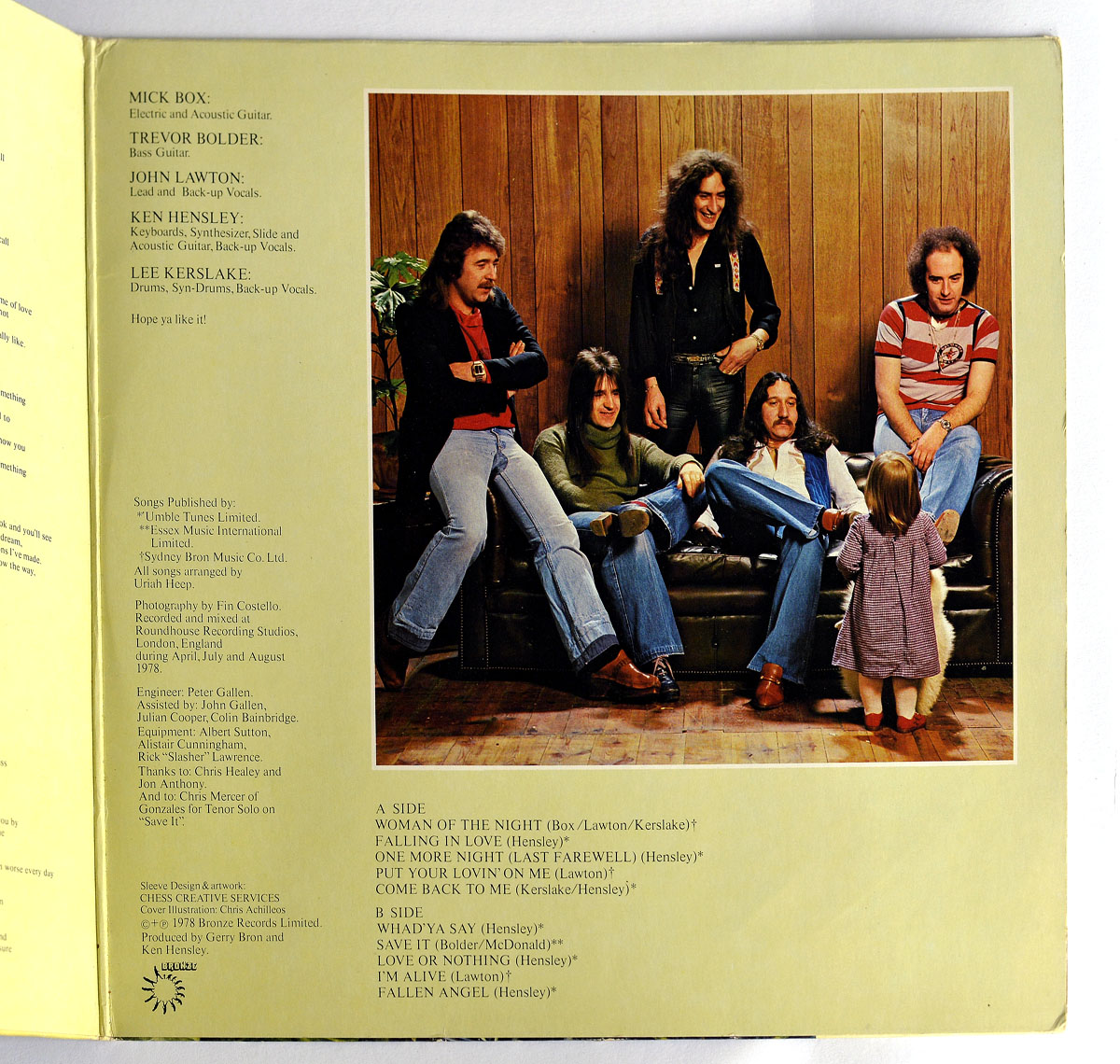 Uriah Heep - Fallen Angel (German Release) right inside page of the gatefold sleeve, showing a color band photo of five members in casual clothing sitting on and around a dark leather couch against a wood-paneled wall, with a small child standing in front of them. To the left, text credits list all musicians, instruments, engineers, recording studios, sleeve design, and track listing details, presented in black print on a pale yellow background.