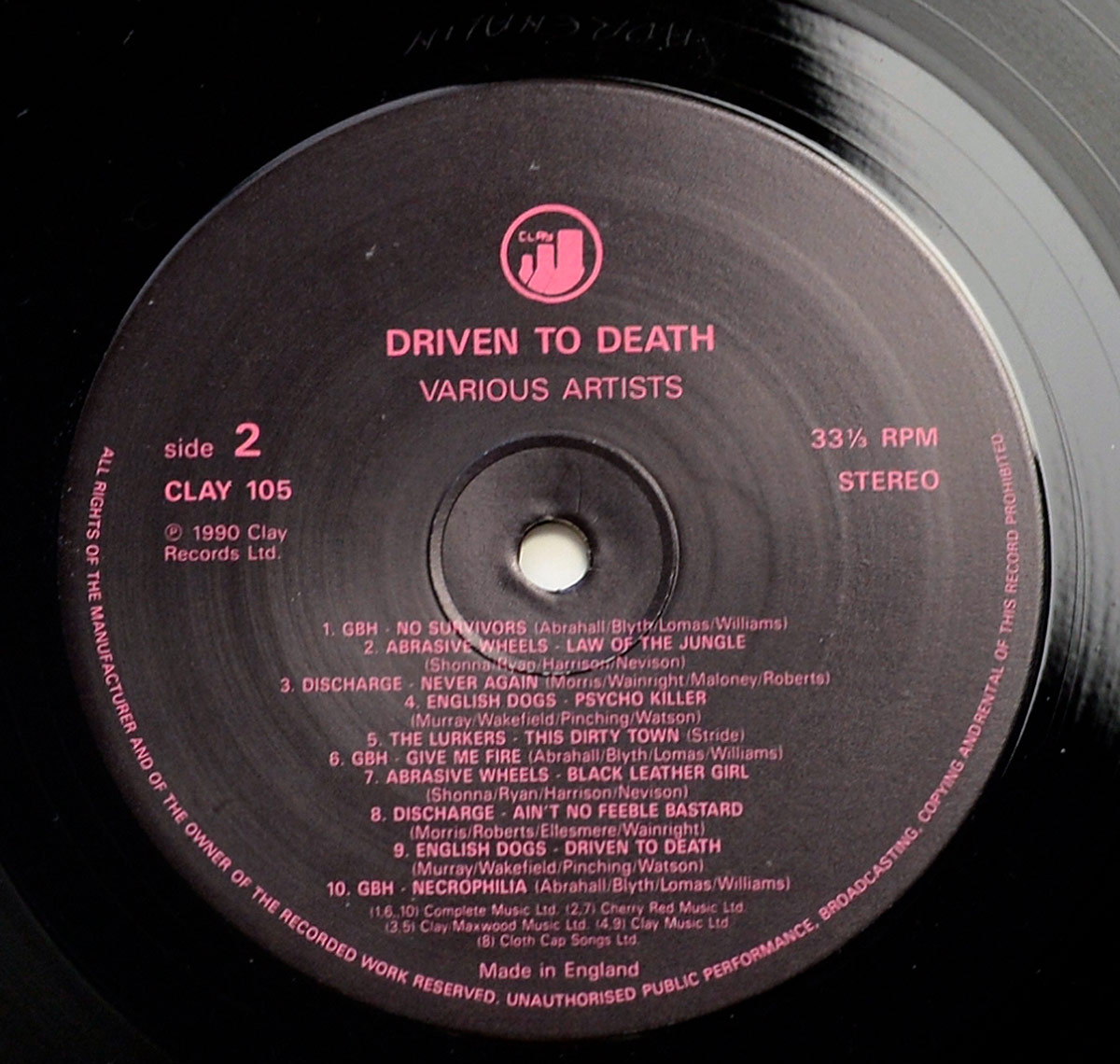 Side 2 record label of VA - Driven to Death punk LP. Red text on black label, listing 10 tracks from G.B.H., Abrasive Wheels, Discharge, English Dogs, and The Lurkers.