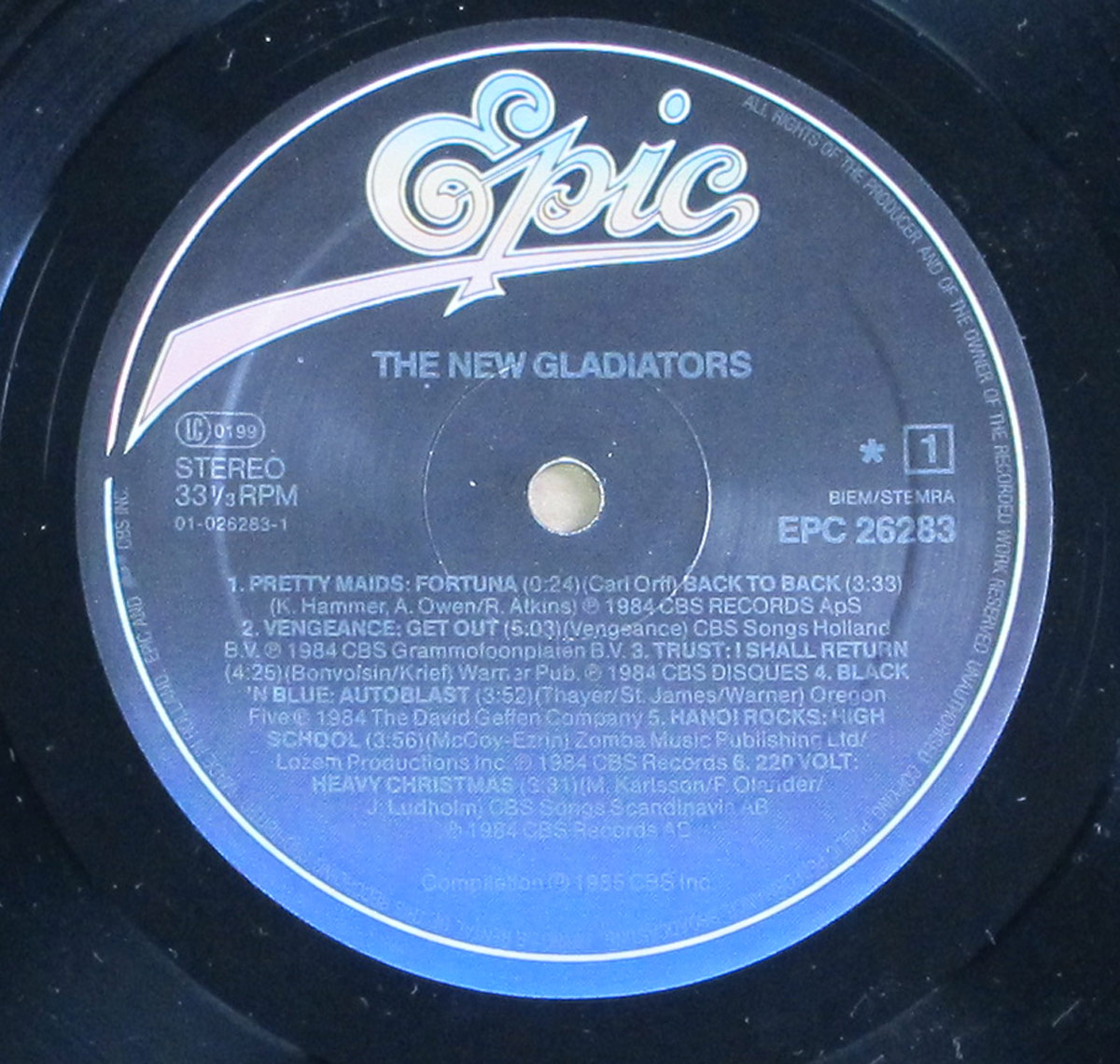 Close-up of Side One label from New Gladiators compilation vinyl, showing band names, song titles, durations, copyright info, and Epic Records logo.