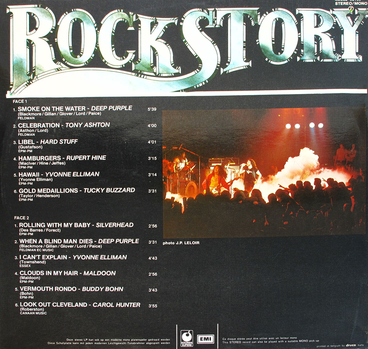 Back cover of the Belgian compilation album Rock Story, released on the Sounds Superb label. The top half features the album title Rock Story in large metallic silver stylized lettering. Beneath it, the left section lists the full track details for Face 1 and Face 2, including titles, artist names, songwriters, publishers, and timings. Tracks include Deep Purple’s Smoke on the Water and When a Blind Man Dies, Tony Ashton’s Celebration, Rupert Hine’s Hamburgers, Yvonne Elliman’s Hawaii and I Can’t Explain, Hard Stuff’s Libel, Tucky Buzzard’s Gold Medallions, Silverhead’s Rolling with My Baby, Maldoon’s Clouds in My Hair, Buddy Bohn’s Vermouth Rondo, and Carol Hunter’s Look Out Cleveland. On the right-hand side, a live concert photograph by J.P. Leloir shows a band under red stage lights, with smoke rising dramatically across the stage and a packed crowd in silhouette. At the bottom are the Sounds Superb and EMI logos, legal text in French and Dutch, and pressing credit to Druco, Belgium.