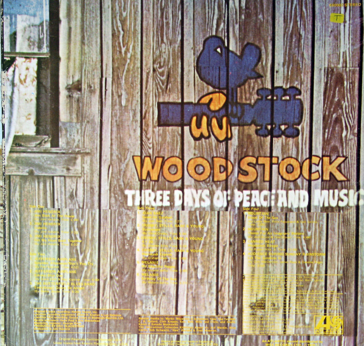 Back cover of Woodstock Two Vinyl 2LP, featuring a rustic wooden wall with the Woodstock dove-and-guitar logo and the words 'Three Days of Peace and Music' along with track listings in yellow text.